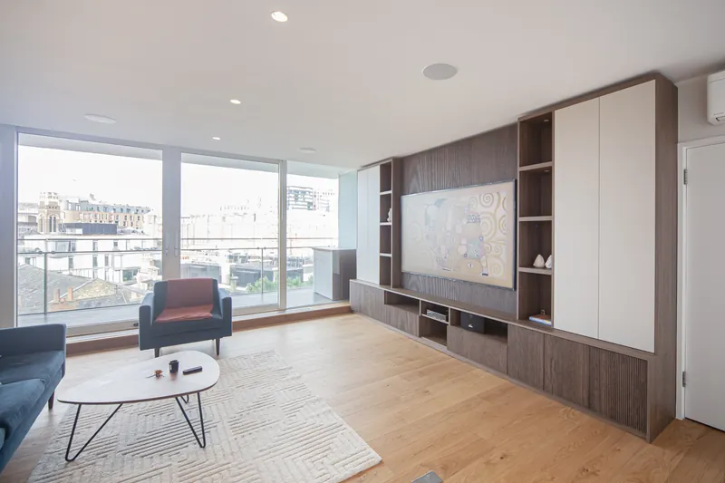 Living room with full-height fluted media wall and tall storage in London SW1E